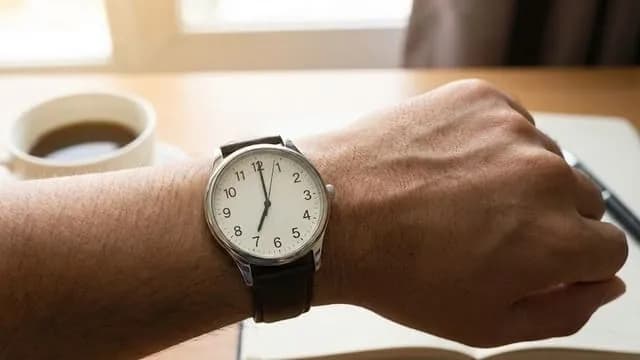 Homem vê as horas 07:07 no relógio de pulso